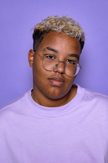 Nanoah Struik tegen een paarse achtergrond. Nanoah komt met COC op voor lhbti+ belangen.